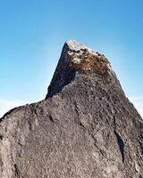 Mossy rock resembling a mountain and blue sky photo