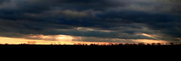 Sunbeams breaking through cloud cover in backlit panorama shot photo