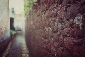 Grungy shot of a narrow alley with cobblestone wall photo