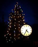 Clock and christmas tree in the night symbolizing christmas time photo