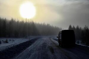 Backlit shot of winter road on a misty day in Lapland photo