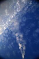 Smoke pillar in a sky with fluffy clouds photo