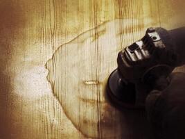 Grungy shot of angle grinder being used to remove old paint from wooden surface photo