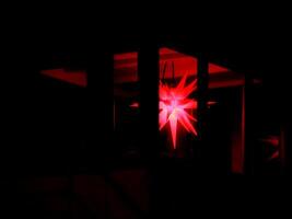 Red Moravian star hanging in a dark patio photo