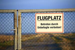 Sign at a a gate saying Flugplatz - Betreten durch Unbefugte verboten Airport - No trespassing by unauthorized personnel photo