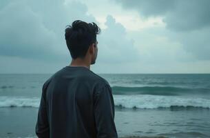 Man stand ocean shore, look into beautiful distance at blue sea waves photo