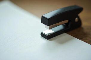 Stapler on white paper, workplace in office, student desk photo