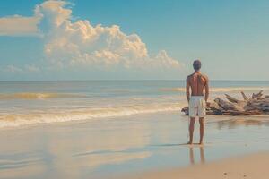 A man standing on the beach looking at the ocean photo