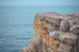 A man standing on a cliff overlooking the ocean photo