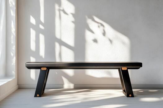 A black bench sitting in front of a window photo