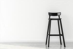 A black stool against a white wall photo