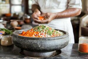 A man is preparing a bowl of food in a kitchen photo