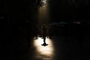 A person walking in the street with the sun shining through the trees photo