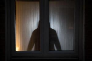 A person is standing in front of a window at night photo