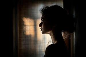 A woman is looking out the window in the dark photo