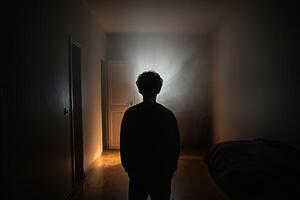 A person standing in a dark room with a light shining from the door photo