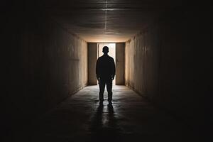 A man standing in a dark tunnel with light coming from the end photo