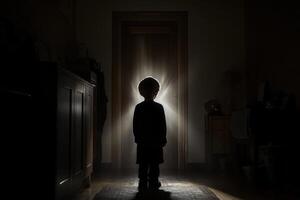 A child standing in the dark in front of a door photo