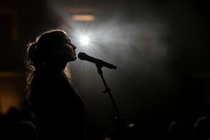 A woman is singing into a microphone in front of a crowd photo