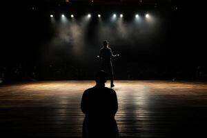 A man standing on a stage with a spotlight photo