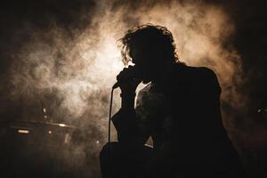 A man in silhouette with a microphone in front of him photo