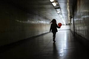 A woman holding a red balloon in a dark tunnel photo