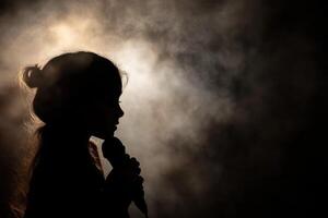 Silhouette of a girl singing in the dark photo
