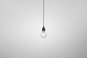 A Single Light Bulb Hanging from a Wire Against a White Wall photo