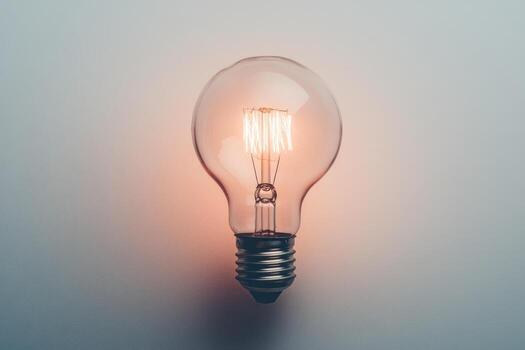 A Single Glowing Incandescent Light Bulb Against a White Background photo