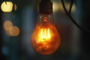 A glowing incandescent light bulb hanging from a wire. photo
