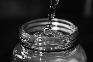 Water Pouring into Glass Jar with Ripples and Reflections photo