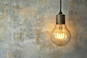 Glowing Light Bulb Against Weathered Concrete Wall photo