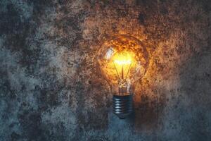 A Glowing Light Bulb Against a Rough, Textured Background photo
