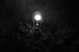 A Lit Lightbulb Amongst Black Rocks photo
