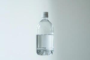 A Clear Plastic Bottle with White Cap Partially Filled with Water photo