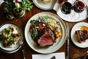 A table with a steak, potatoes, and wine photo