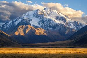 Majestic snow capped mountain range at sunset over golden grasslands photo