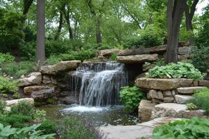 Serene Waterfall Cascading Through Lush Garden Rocks photo