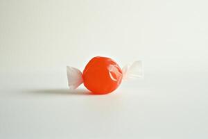 Single Orange Hard Candy Wrapped in White Paper photo