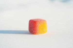 A Single Sugary Gummy Cube Rests On White Snow photo