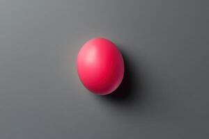 A single pink sphere rests on a grey surface photo
