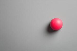 A single pink sphere rests on a gray background photo