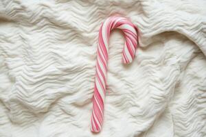 A Peppermint Candy Cane Rests On Soft White Fabric photo
