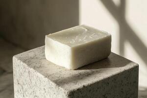 A single bar of off white soap rests on a stone pedestal photo