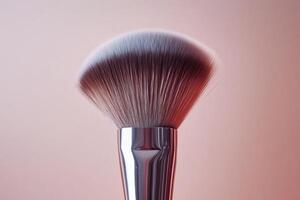 A Closeup of a Powder Brush Against a Soft Pink Background photo