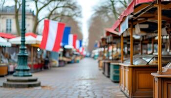 Festive market stalls and flags line a cobblestone street. photo