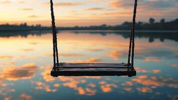 Empty swing over calm lake at sunset photo