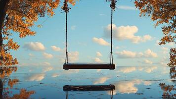 Empty swing over calm water, autumn leaves photo