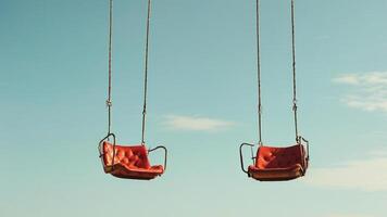 Two empty swings against a clear blue sky. photo