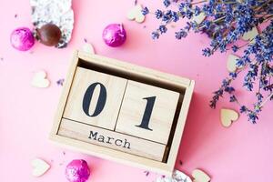 Wooden calendar with the date of March 1 on a pink background, a place for an inscription, The first day of spring, a dry branch of lavender photo